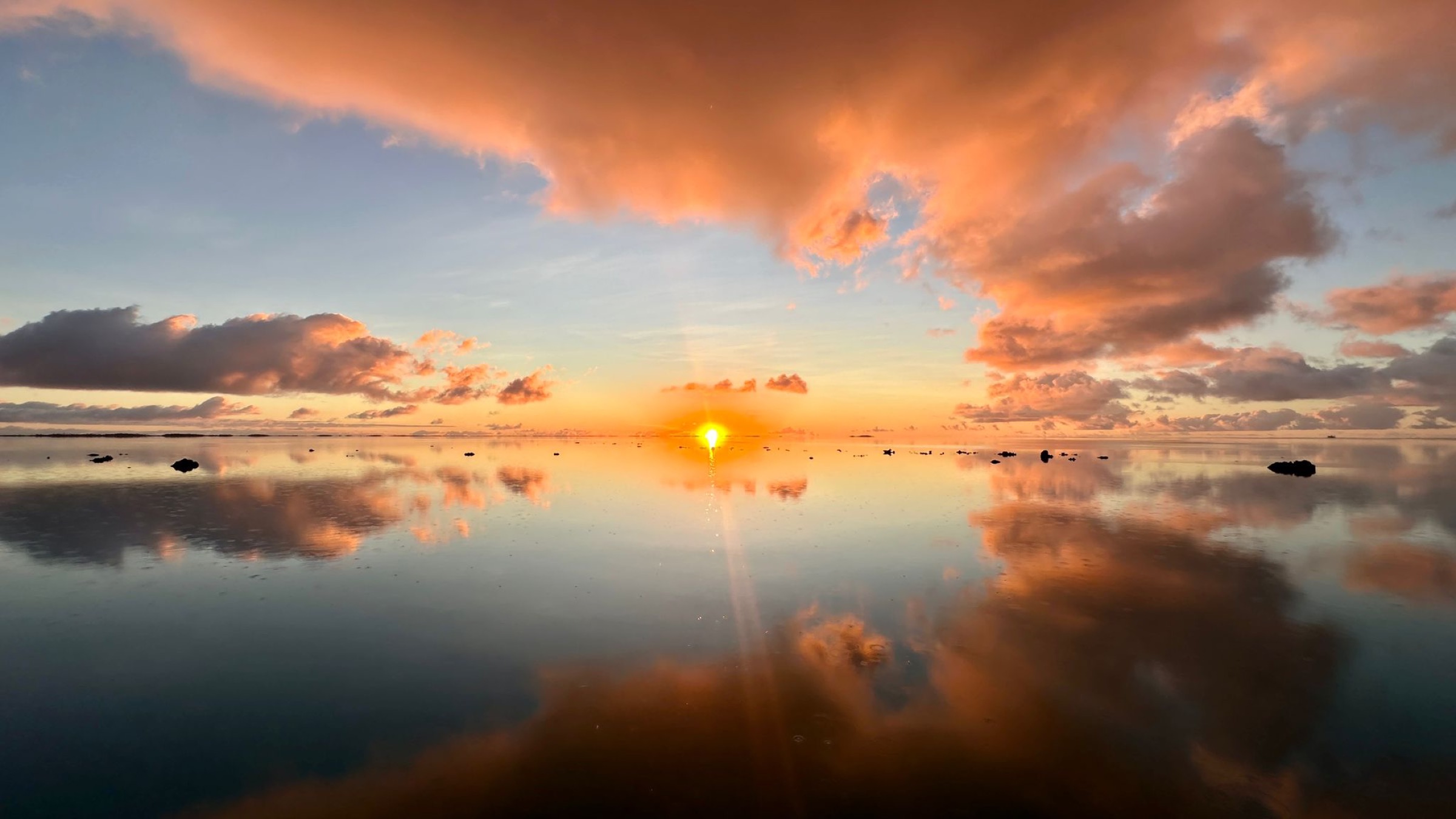 Coucher de soleil se reflétant sur un lagon parfaitement calme, Polynésie française